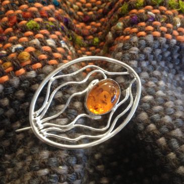 A brooch with oval amber stone